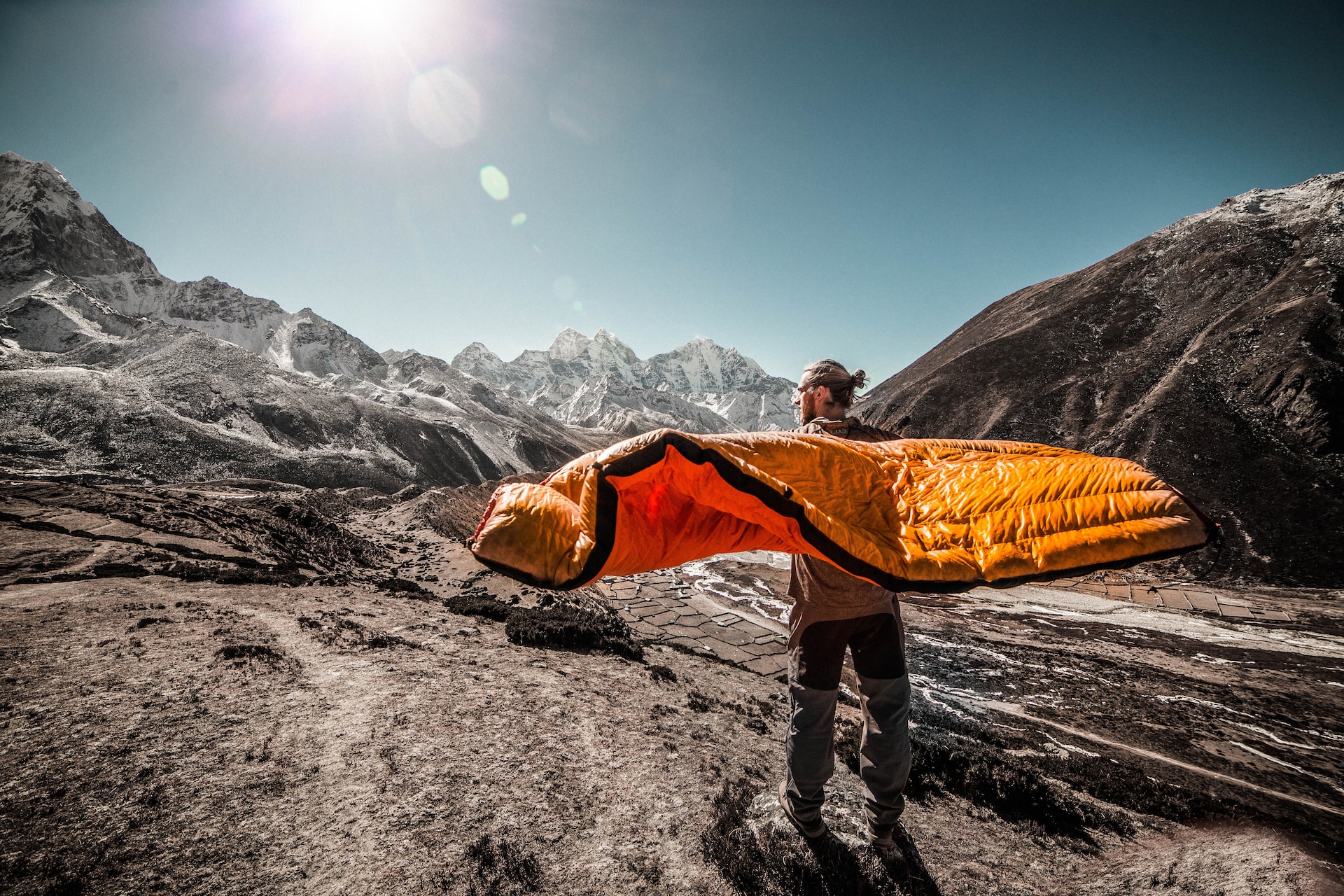 how to choose a sleeping bag: man standing on field between cliffs