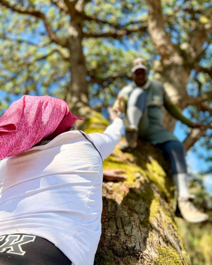 A hiker wearing our pink neck gaiter being helped up.