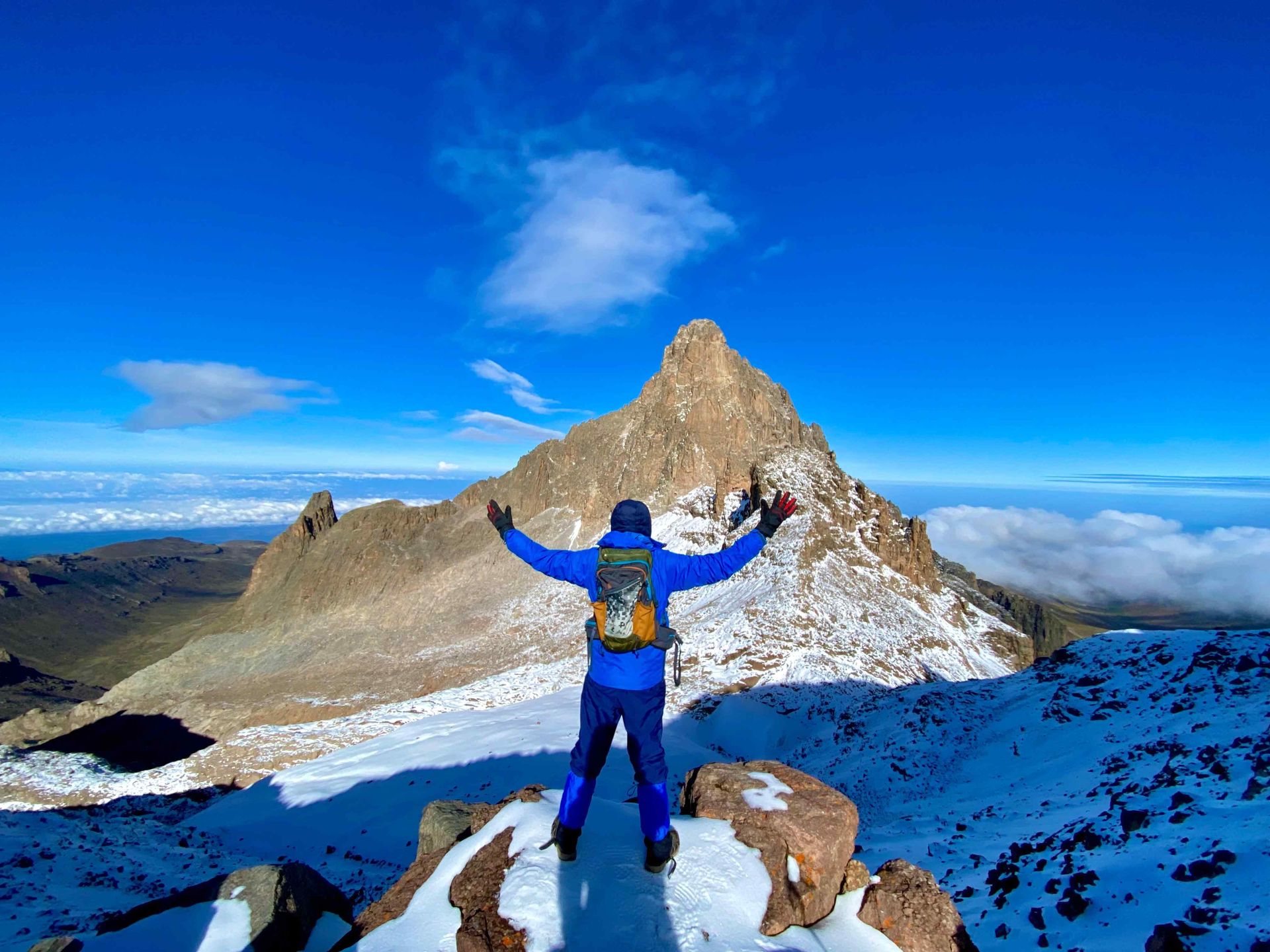 hiker in blue attire strikes a pose facing Batian and Nelion, Mount Kenya highest peaks | train for Mount Kenya, Outdoorer KE